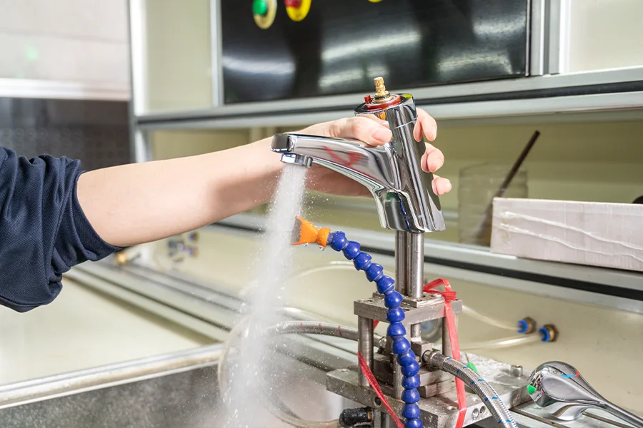 A technician conducting air and water pressure testing on a faucet, a critical quality control step in faucet manufacturing