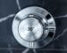 A close up of a polished chrome thermostatic shower mixer valve on a dark marble wall, highlighting precision temperature control.