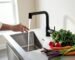 A matte black touchless kitchen faucet operating hands-free in a modern hygienic kitchen.
